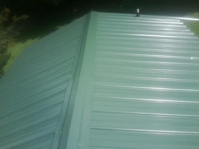 New green metal panels meeting at the ridge of a roof — Flat Roof Repair work by our crew in Kimberly